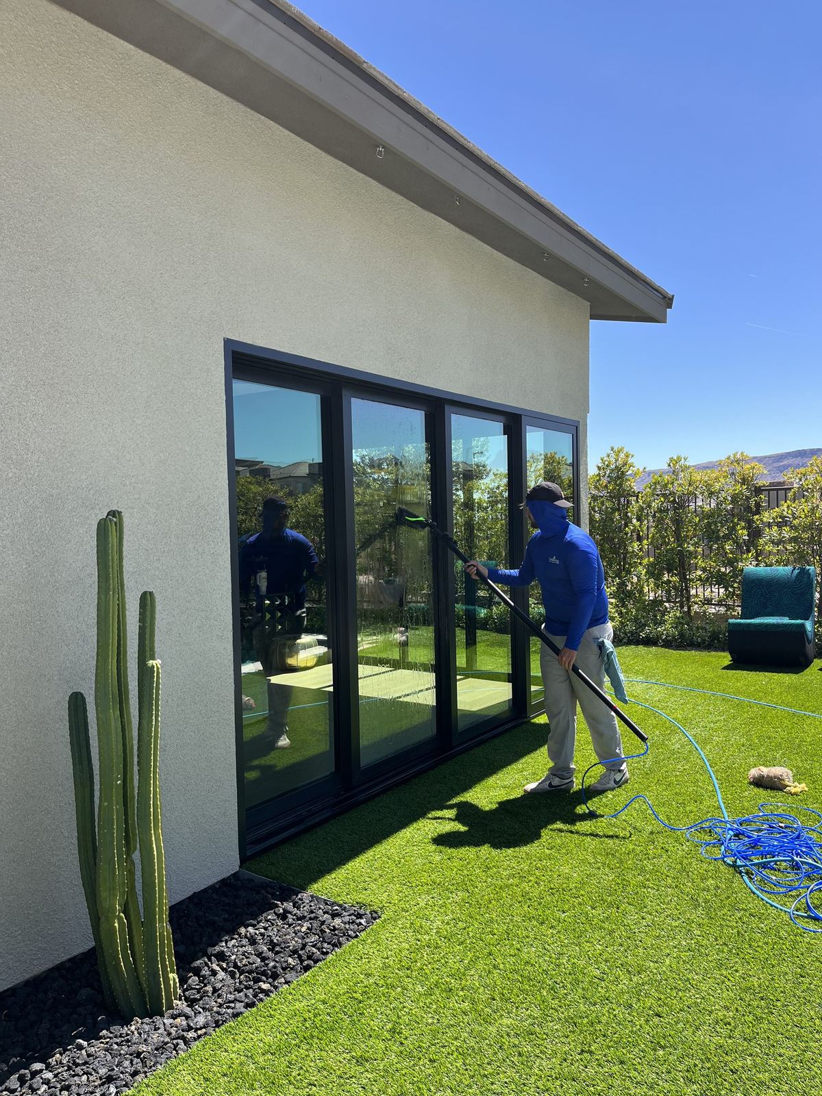 A SLATE technician washing a glass slider at a Summerlin home